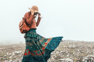 Boho woman wearing hat and leather jacket walking in mountains. Cold weather and fog. Spring or fall hiking. Wanderlust.